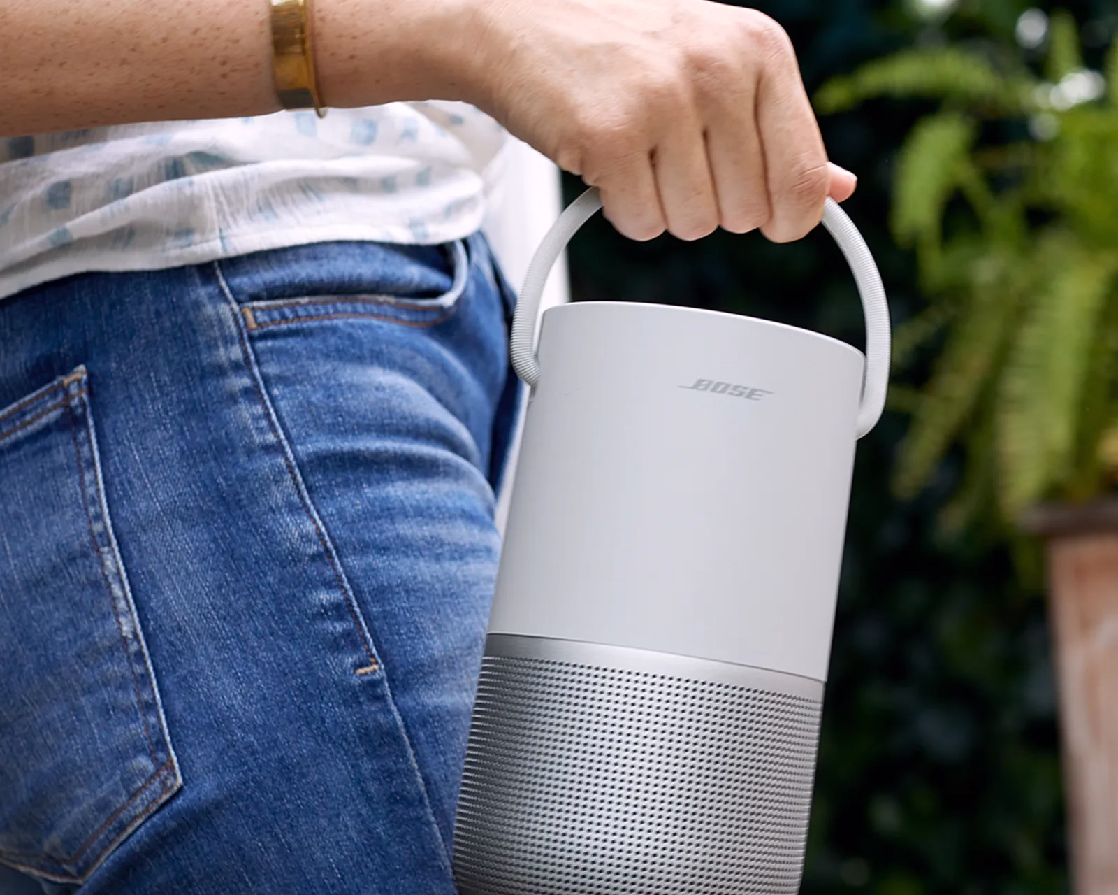 Woman carrying a Bose Portable Smart Speaker outside.