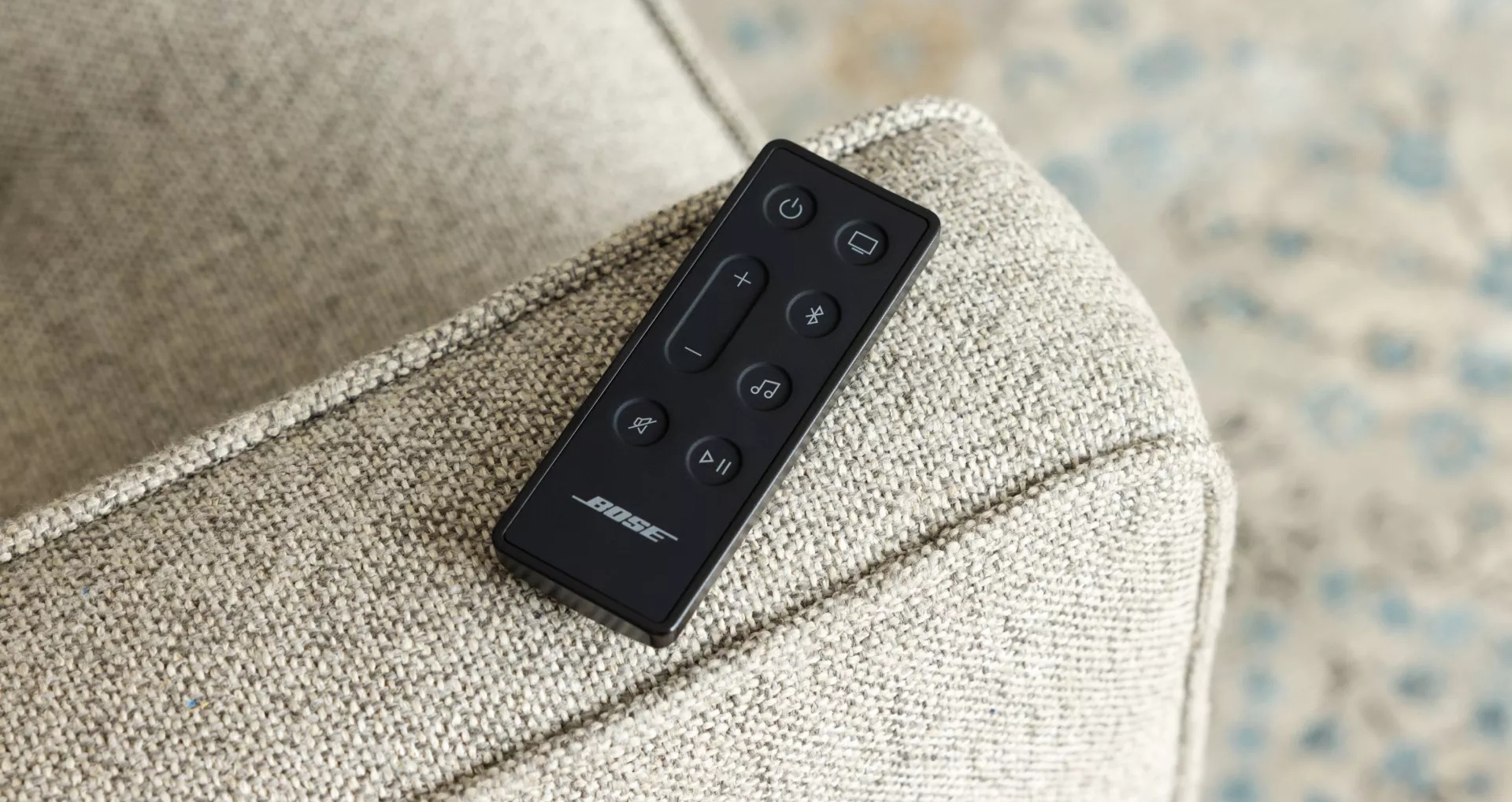 Bose Smart Soundbar 600 remote on the arm of a couch