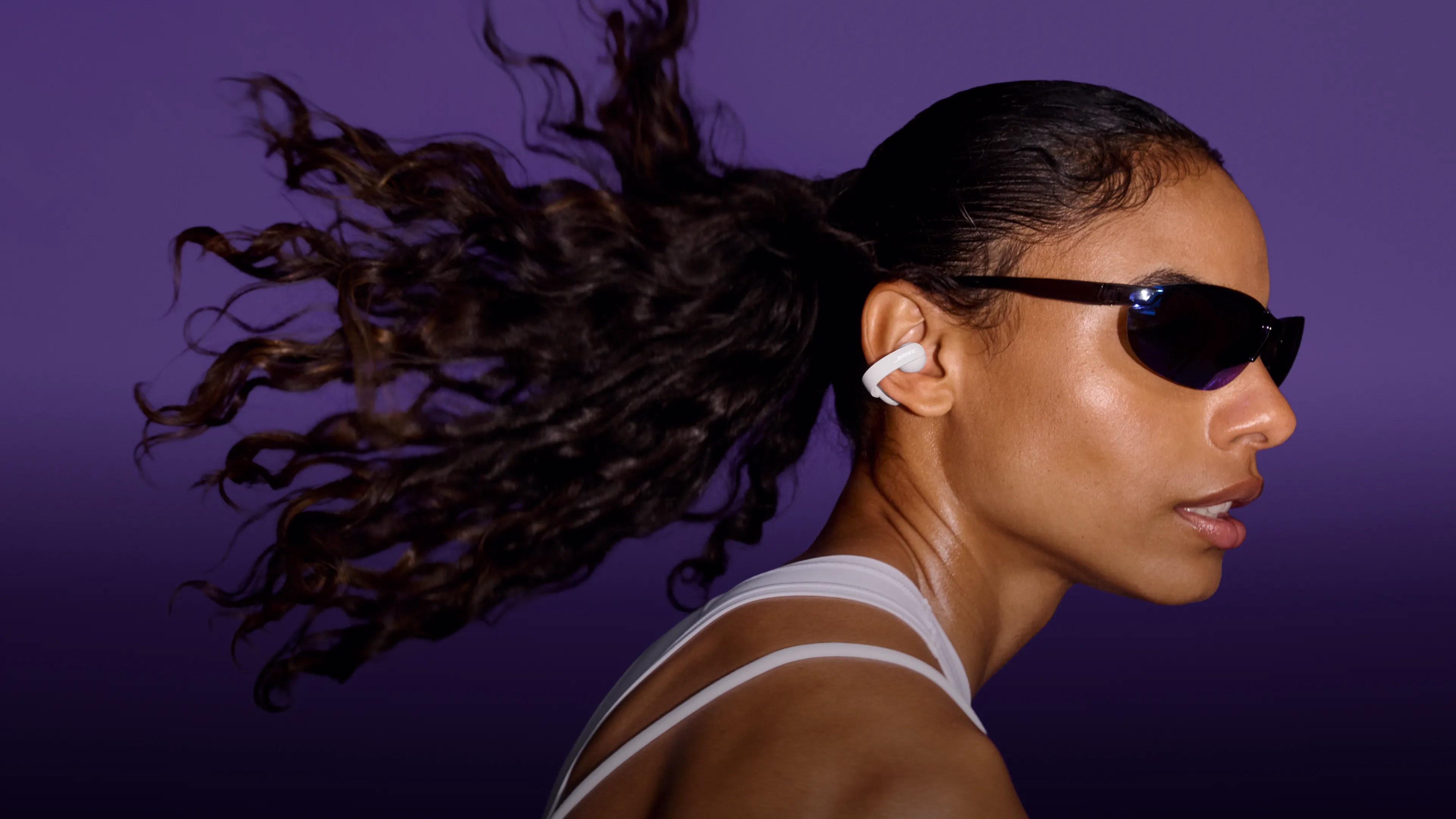 Femme portant des lunettes de soleil et les &eacute;couteurs oreilles libres Sport Bose en faisant du sport.