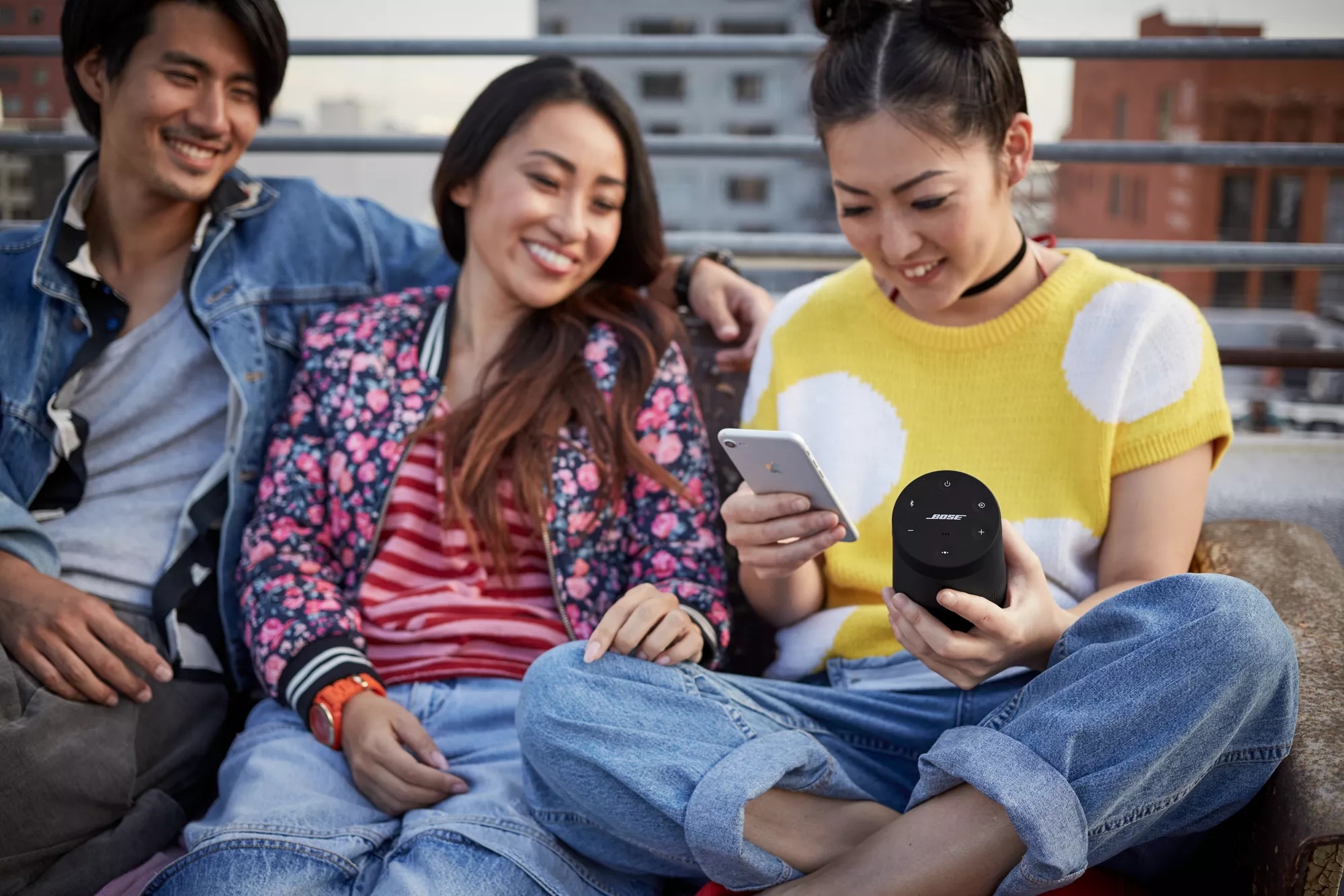 Group of friends sitting on rooftop listening to music on SoundLink Revolve II Speaker