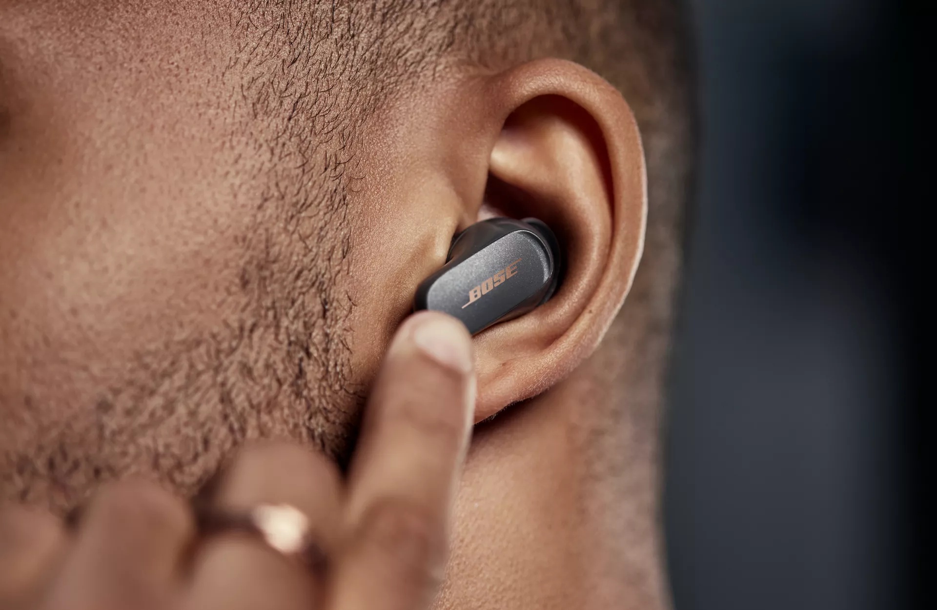 Man swiping the left earbud of the Bose QuietComfort Earbuds II to adjust volume