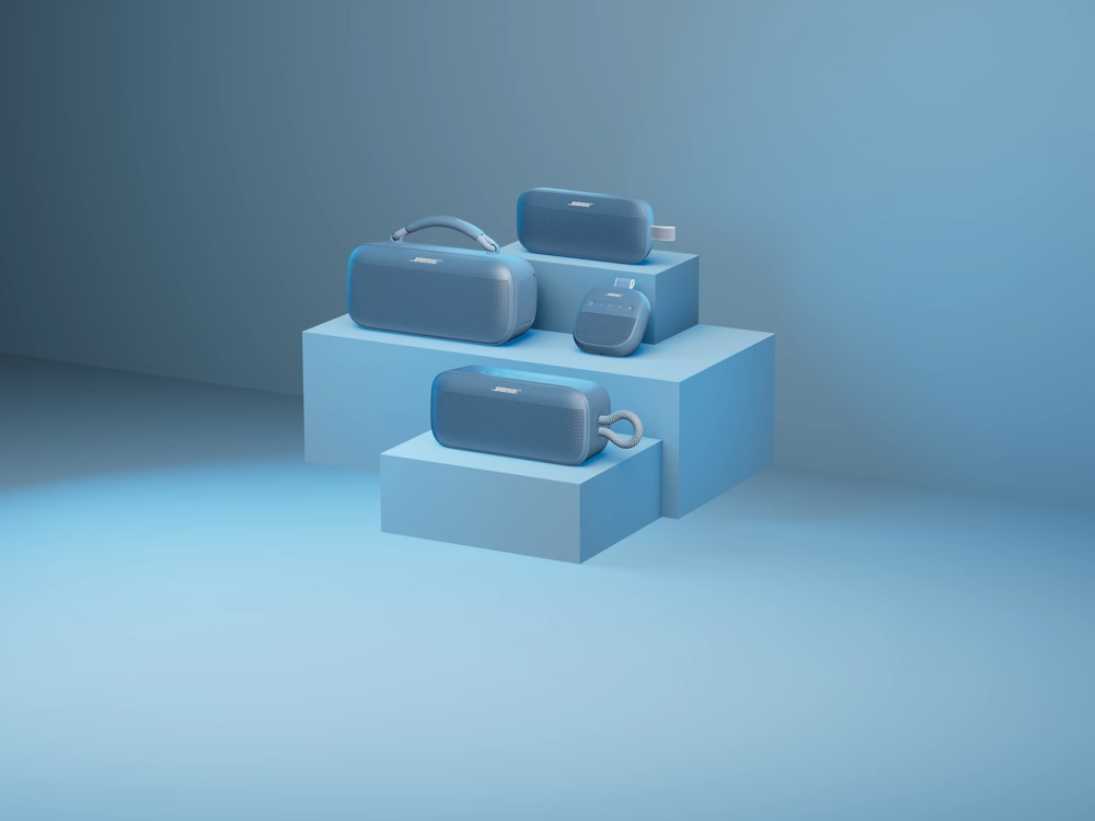 SoundLink Flex Bluetooth Speaker (2nd Gen), SoundLink Max Portable Speaker, SoundLink Micro Bluetooth Speaker (2nd Gen), and SoundLink Plus Portable Speaker displayed on tiered blocks in a clean monochromatic blue setting. 