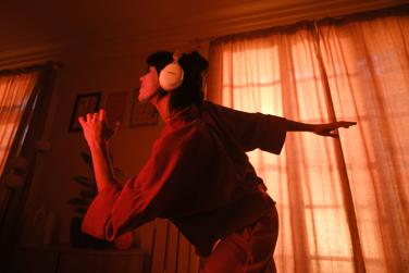 Woman dancing in a warmly lit room while wearing QuietComfort Ultra Headphones (2nd Gen), with sunlight filtering through curtains in the background.