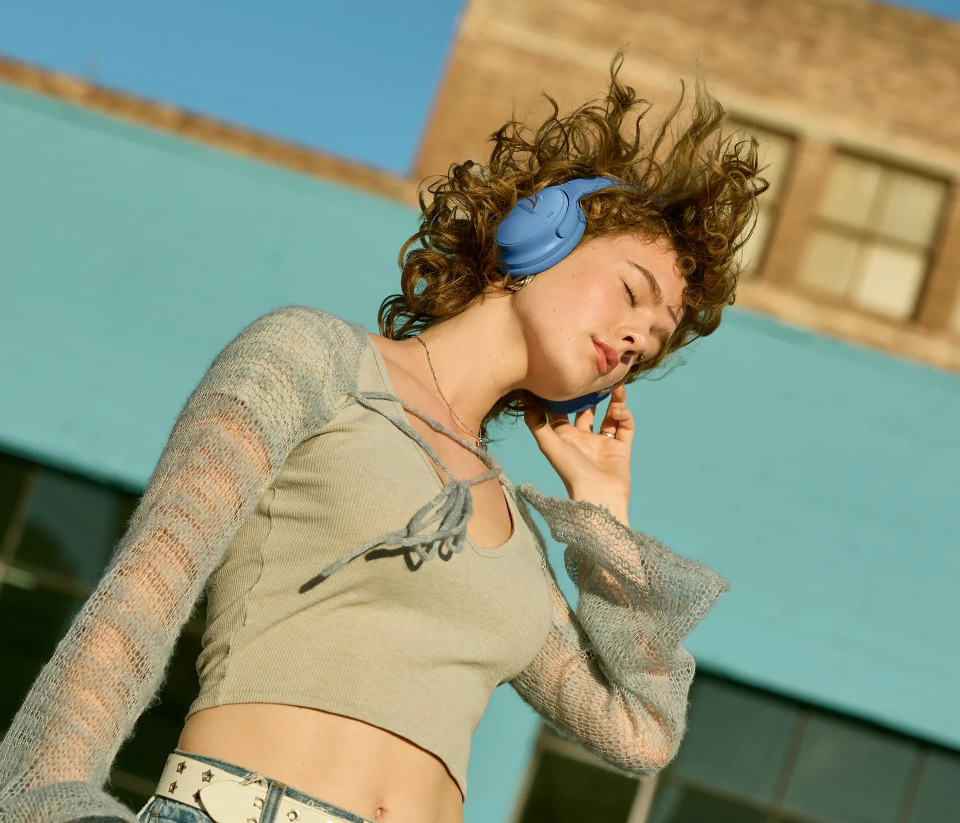 Woman listening to music wearing Blue Dusk QuietComfort Headphones outside.