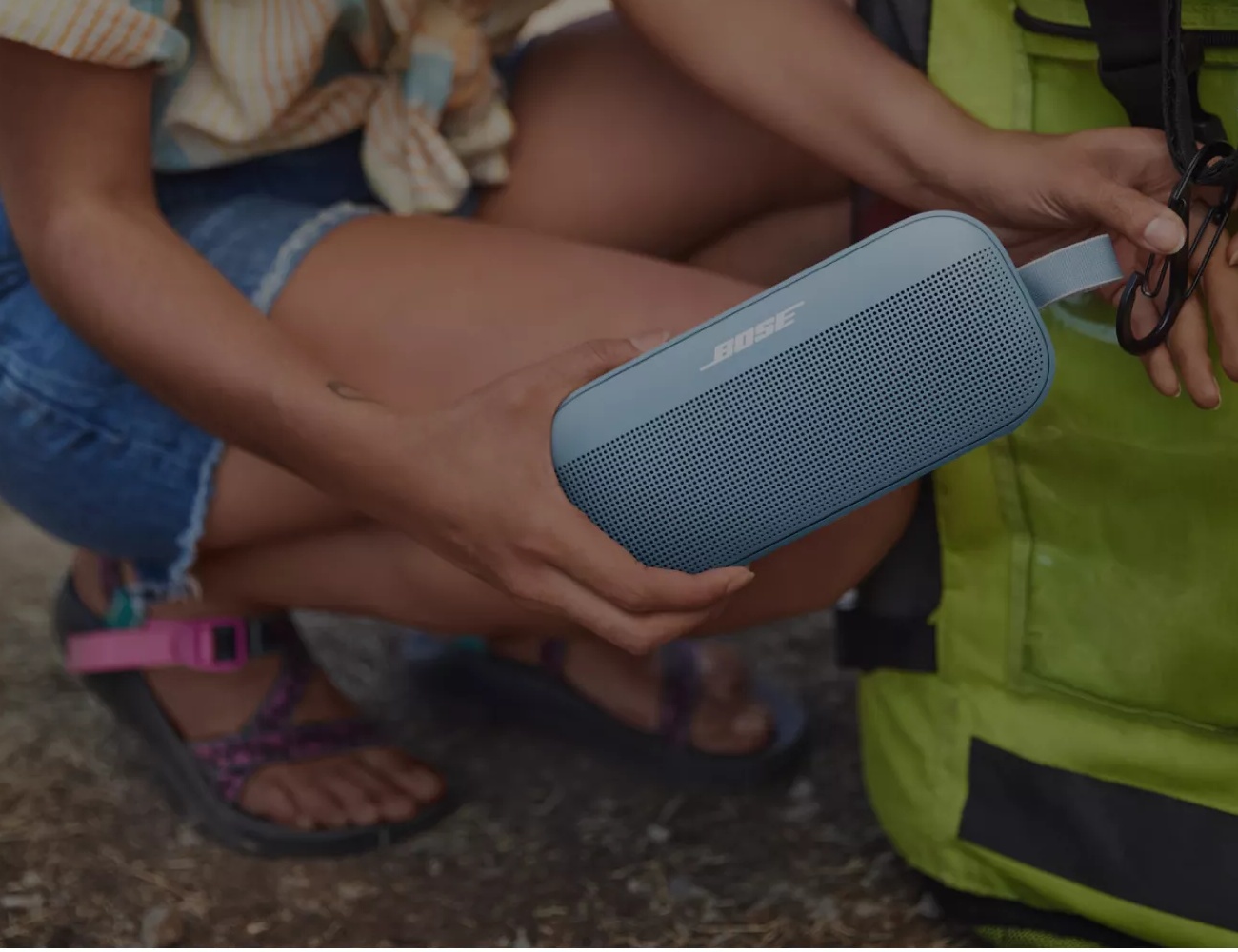 Woman attaching a Bose SoundLink Flex Bluetooth Speaker to her backpack