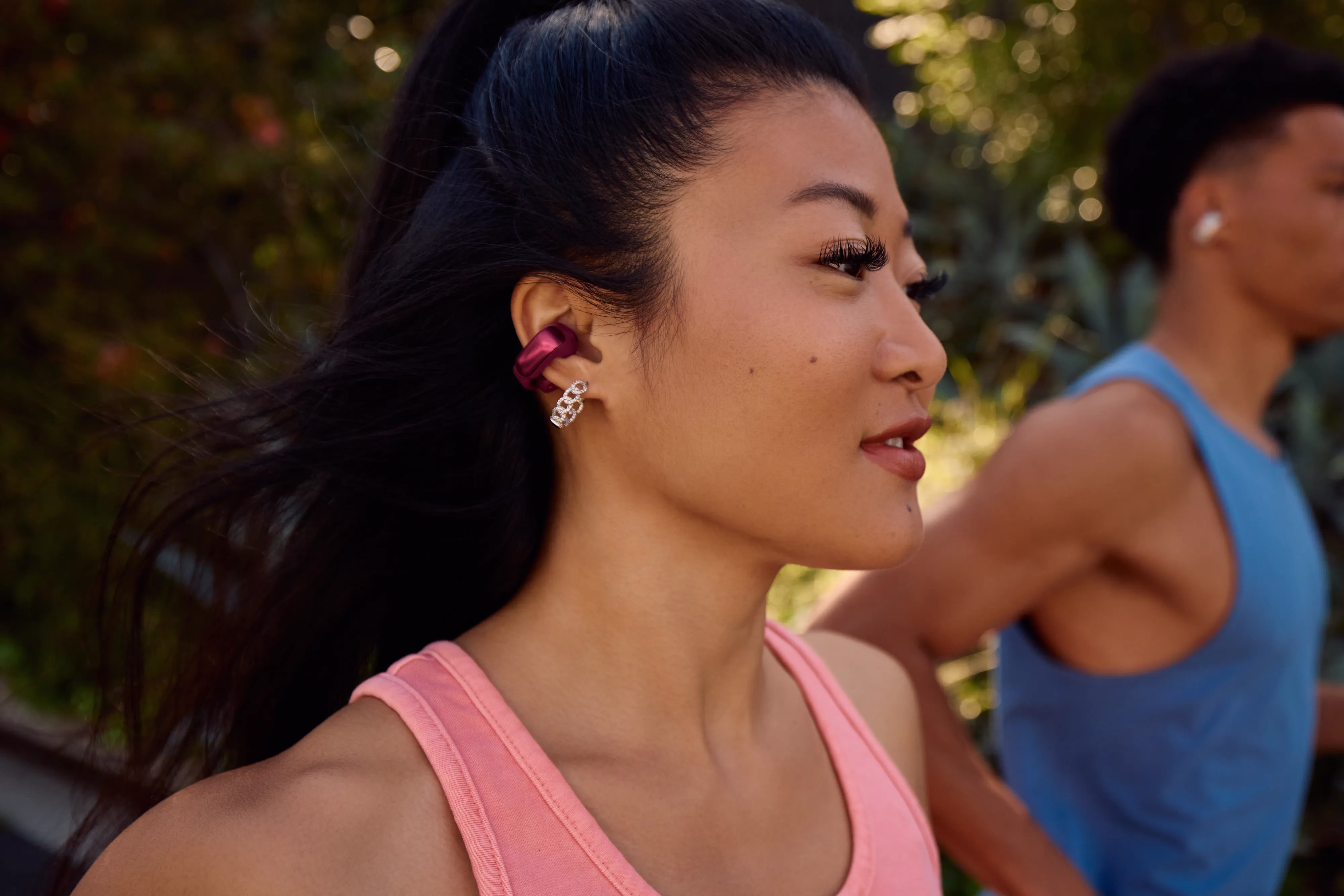 Woman exercising outside while listening to music with her Bose Ultra Open Earbuds