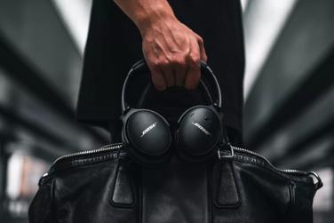 A hand holding a leather bag and Bose QuietComfort 45 headphones