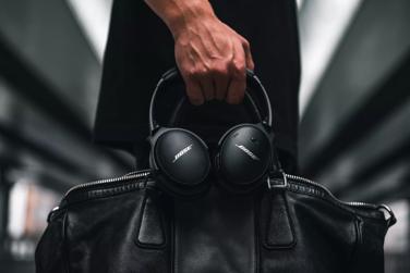 A hand holding a leather bag and Bose QuietComfort 45 headphones
