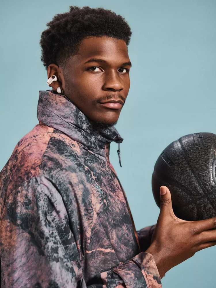 Anthony Edwards qui tient un ballon de basketball, tout en portant des écouteurs oreilles libres Bose Ultra