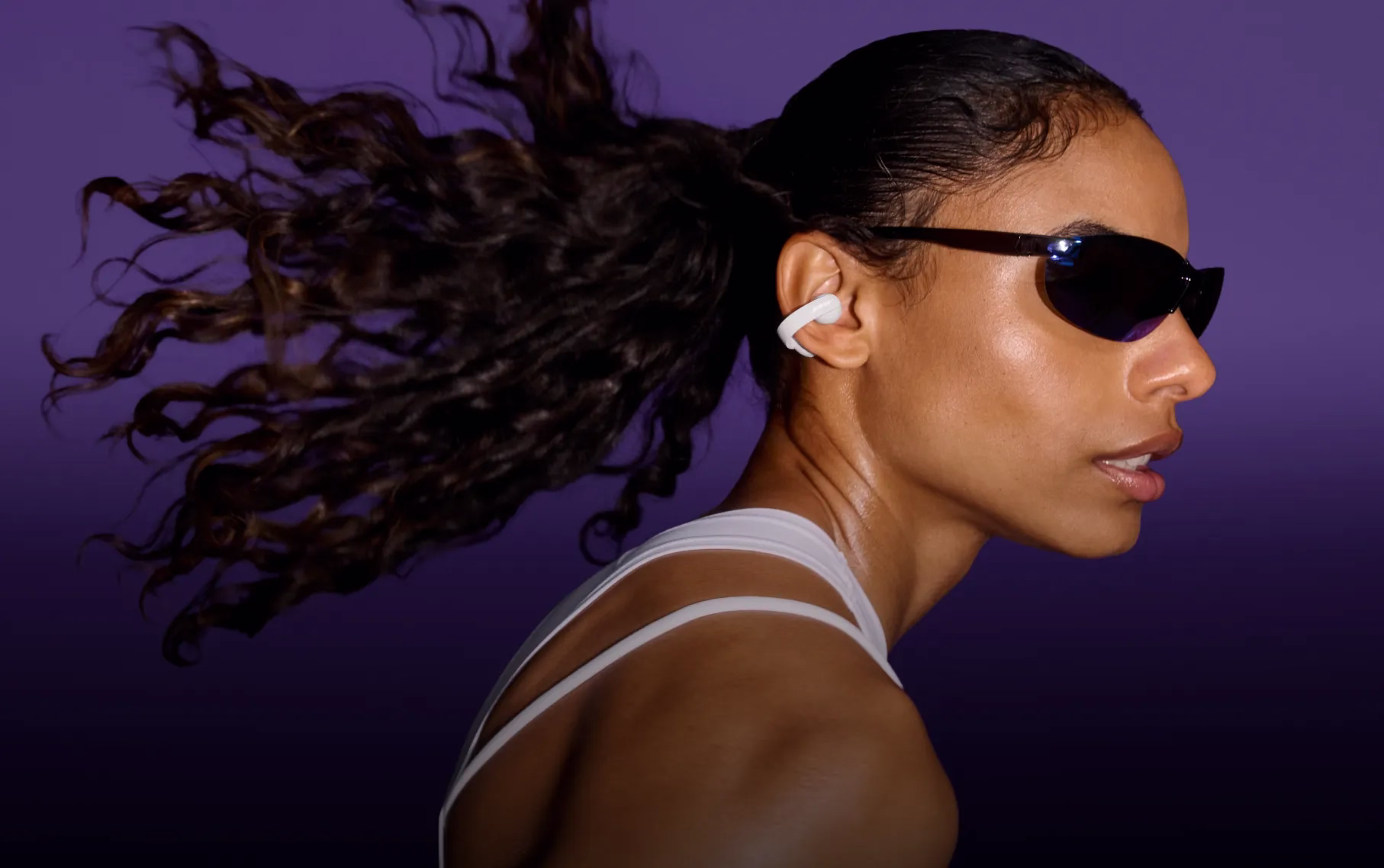 Woman wearing Bose Sport Open Earbuds while working out while wearing sunglasses.