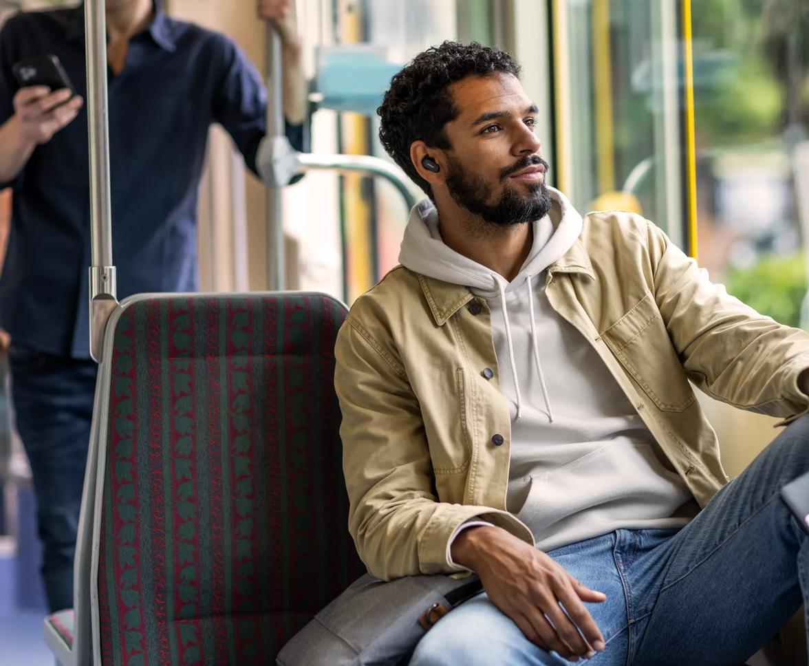 Man sitting on a bus wearing Bose QuietComfort Earbuds II