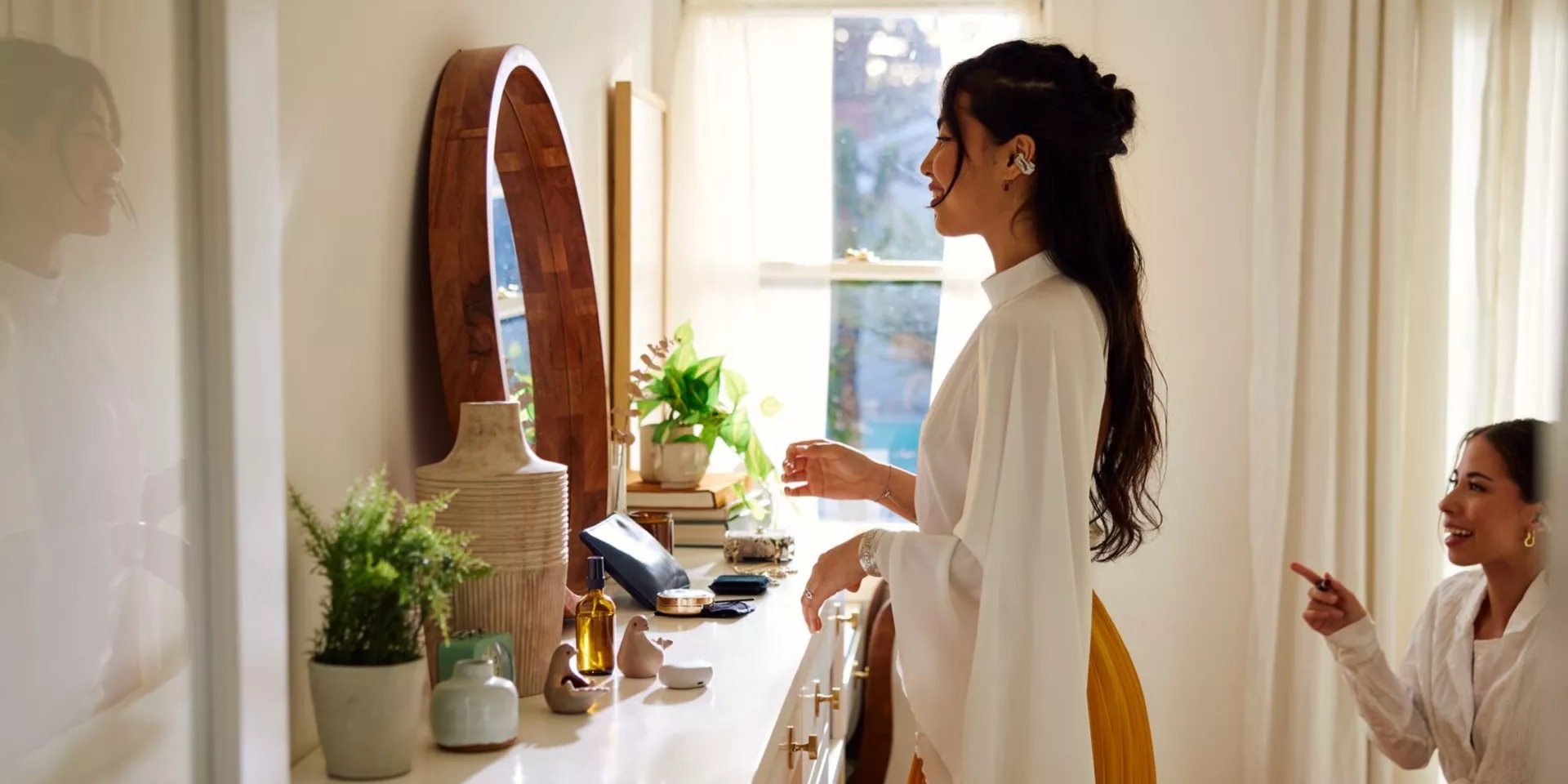 Woman getting ready for the day in her bedroom wearing Bose Ultra Open Earbuds