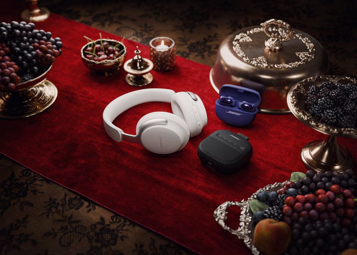 Bose QuietComfort Ultra Headphones (2nd Gen), Ultra Open Earbuds, and SoundLink Micro Portable Speaker (2nd Gen) on a table decorated for Christmas.