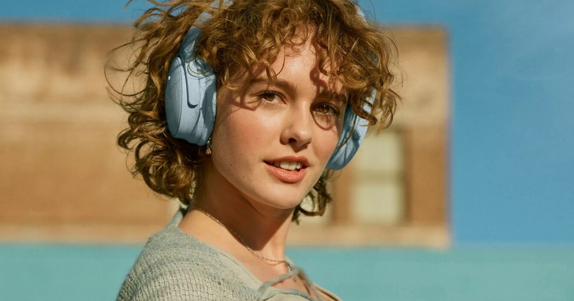 Femme portant le casque Bose QuietComfort en bleu pierre de lune à l’extérieur