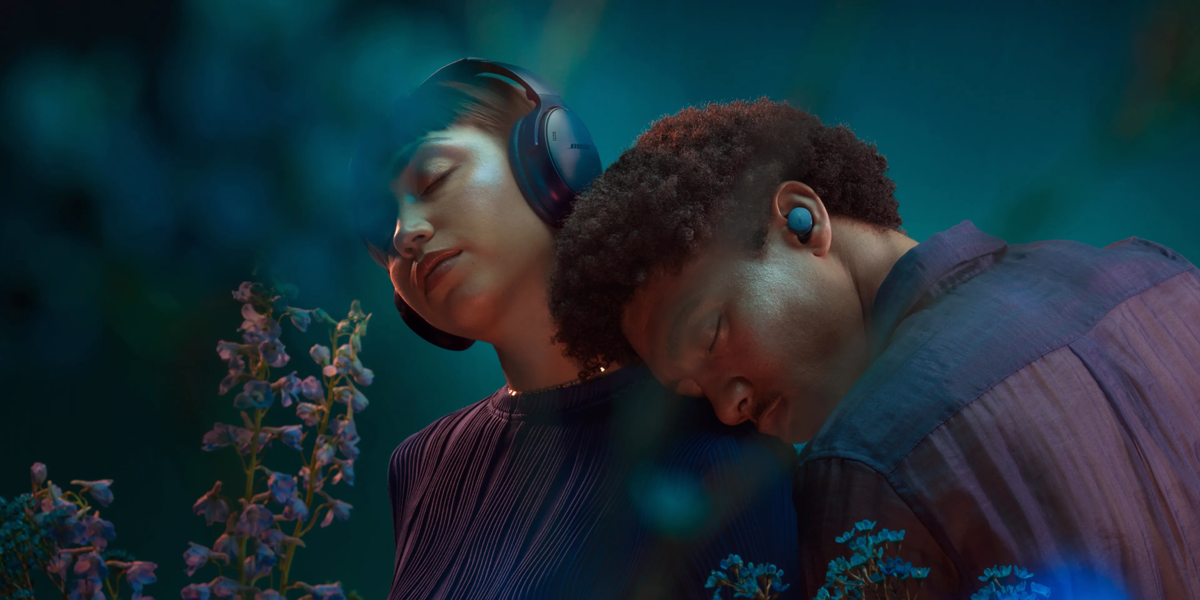 A woman wearing Bose QuietComfort Headphones and a man wearing QuietComfort Earbuds in Twilight Blue.