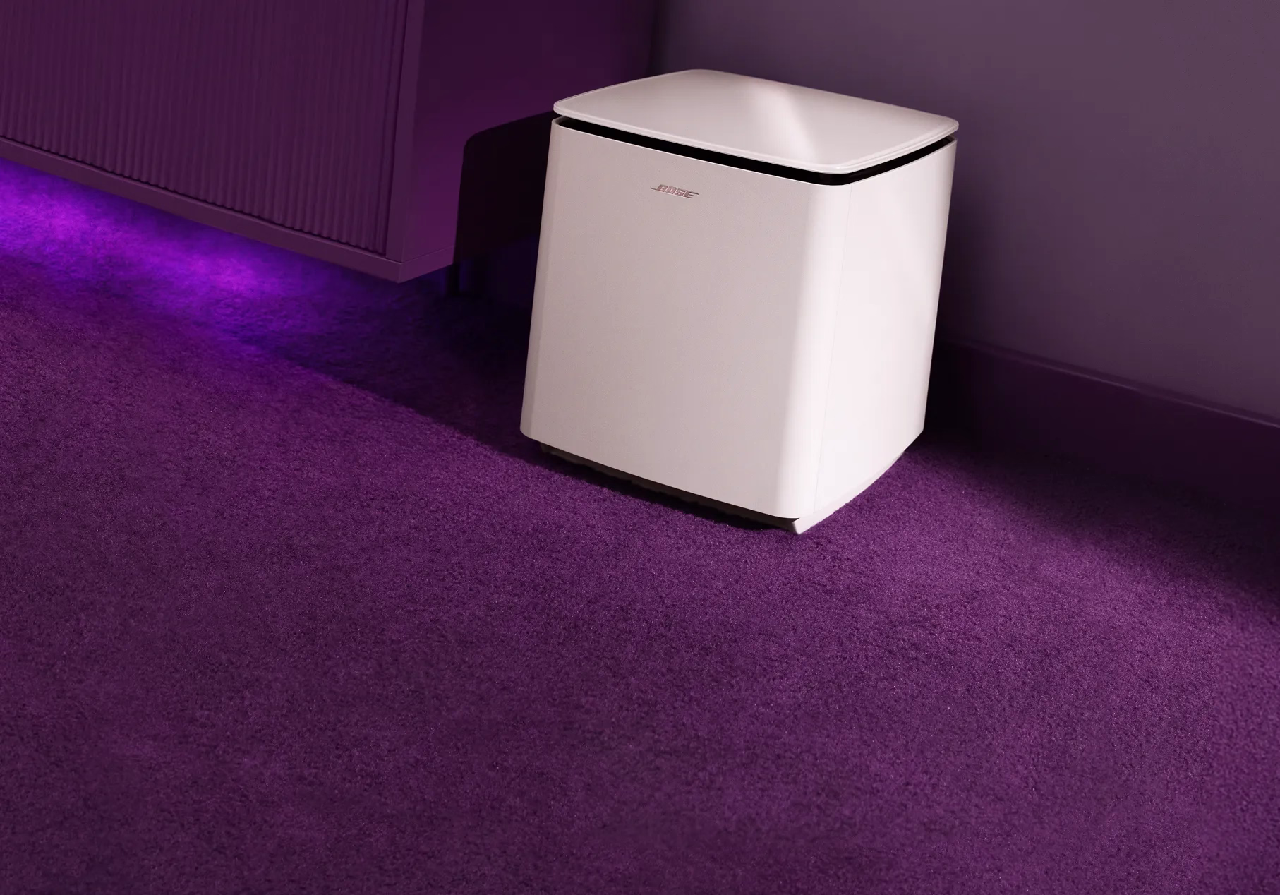 Bose Lifestyle Ultra Subwoofer on a living room floor next to a TV console. 