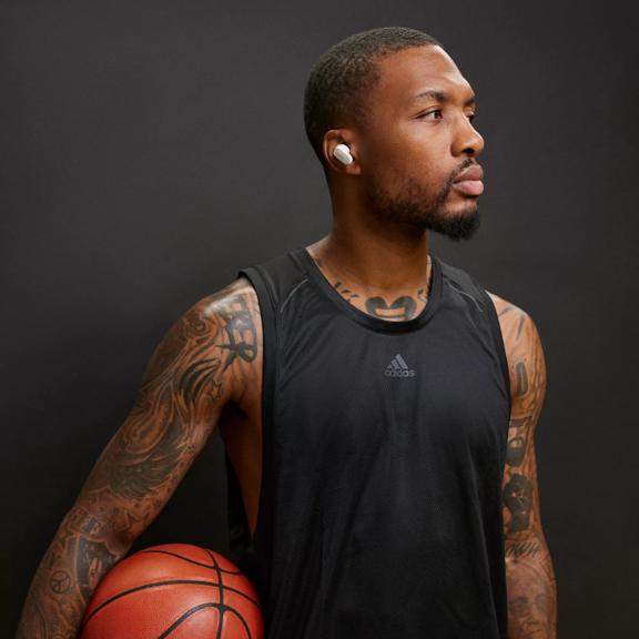 Damian Lillard portant des &eacute;couteurs QuietComfort II de Bose tout en tenant un ballon de basket.
