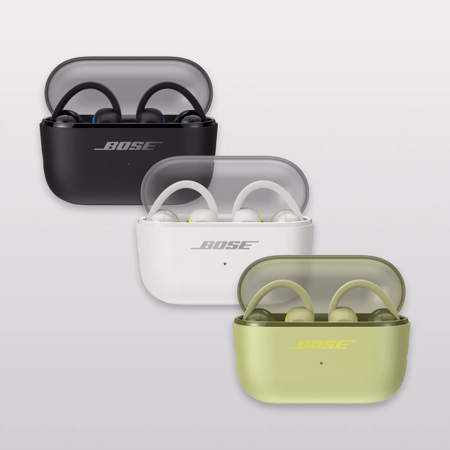 Bose Sport Open Earbuds in their charging case in Black, White Smoke and Eucalyptus Green.