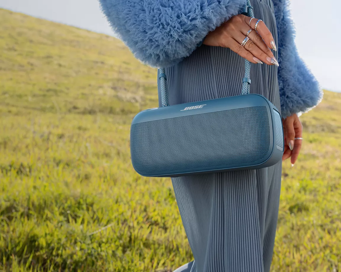Woman walking in a field carrying a Bose SoundLink Max Portable Speaker using the  SoundLink Max Rope Carrying Strap