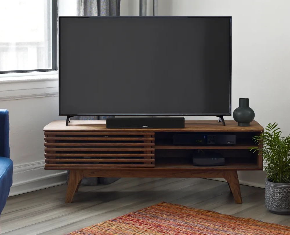 A TV and a Bose Smart Soundbar on a TV console in a living room.