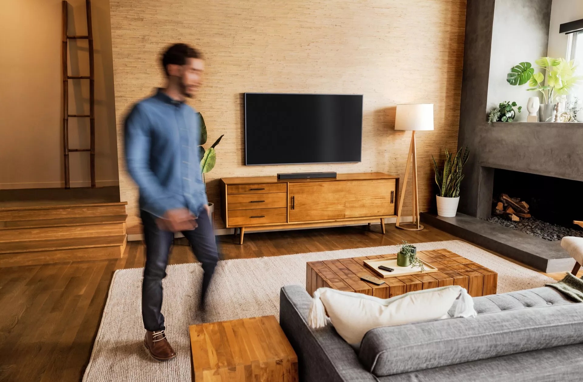 Un homme dans un salon avec une télévision et une barre de son Bose Smart Soundbar 600.