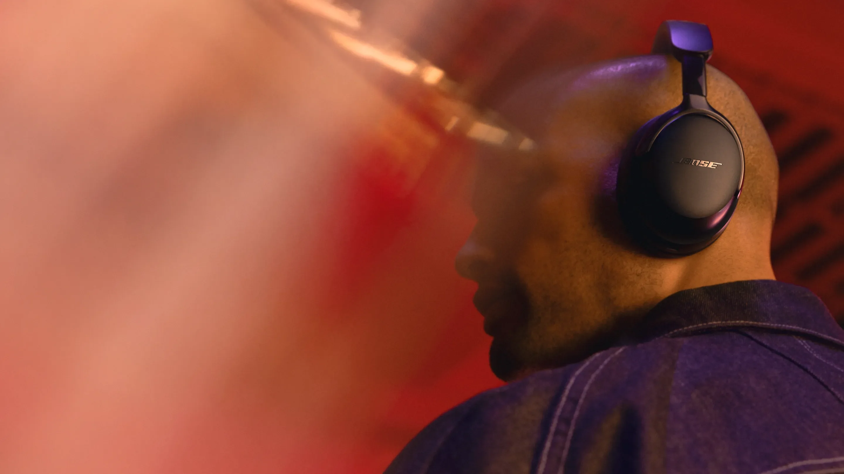 A listener wearing Bose headphones in warm evening light