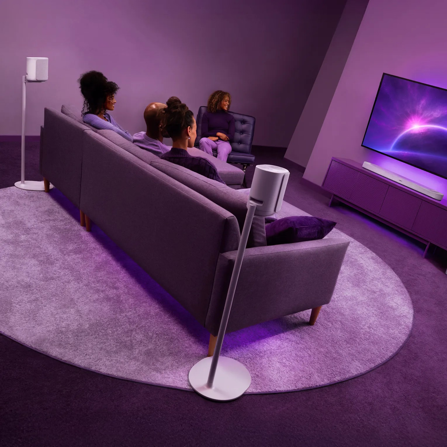 Bose Lifestyle Ultra Soundbar、フロアスタンド上のLifestyle Ultra Speaker、Lifestyle Ultra Subwooferが設置されたリビングルームでテレビを楽しむ友人たち。