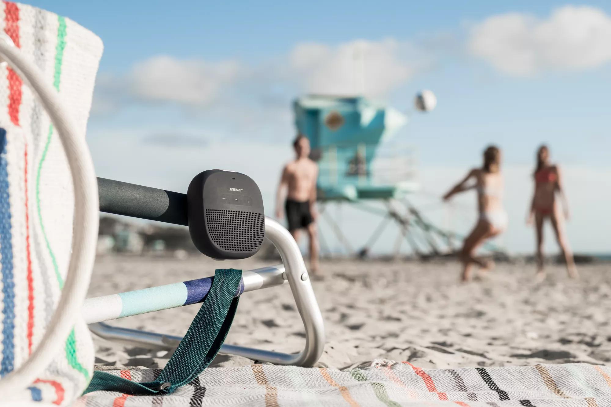 A SoundLink Micro Bluetooth speaker attached to a chair at the beach