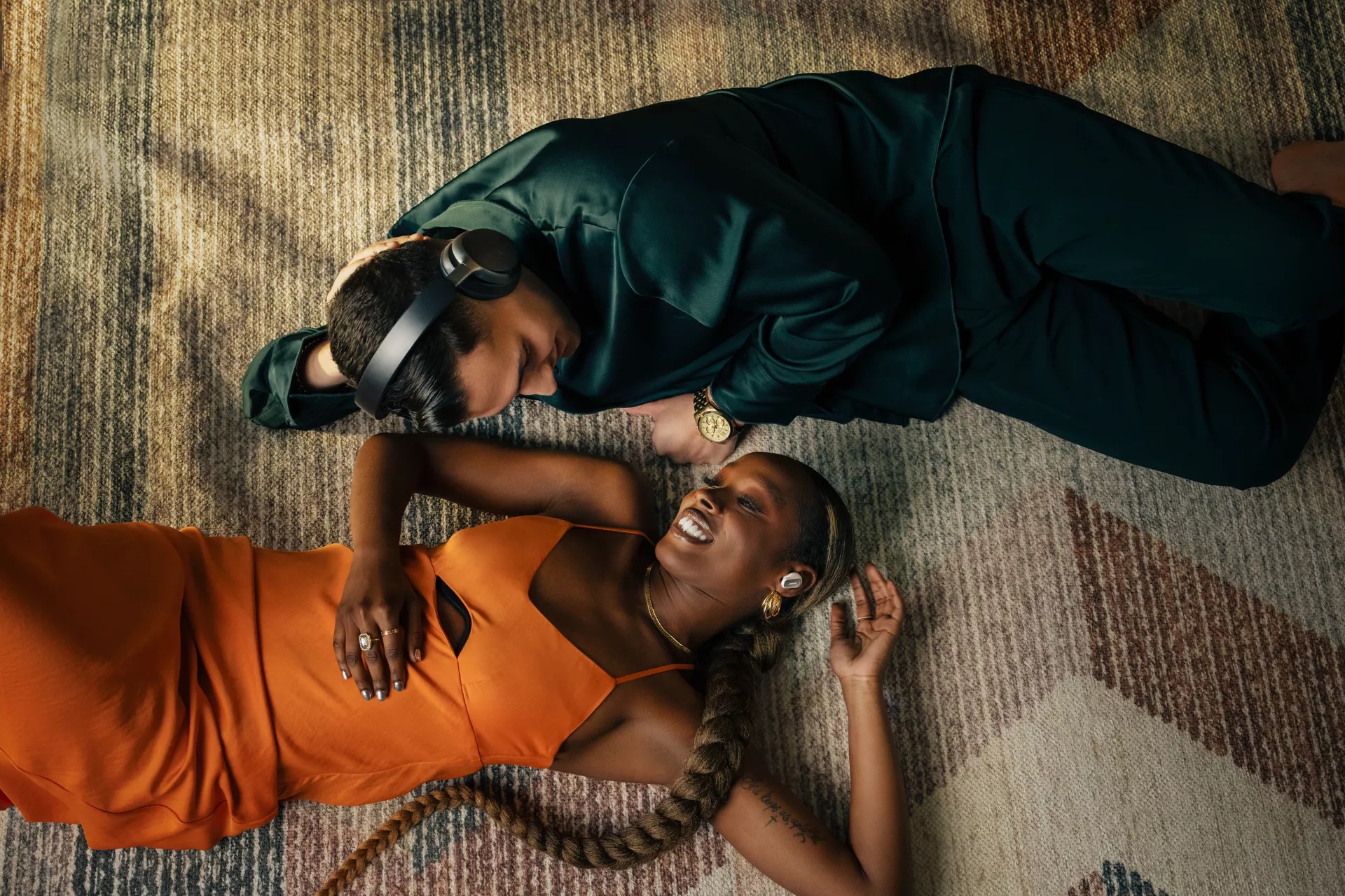 Couple lying on carpet listening to QuietComfort Ultra Headphones and Earbuds without cords tangling
