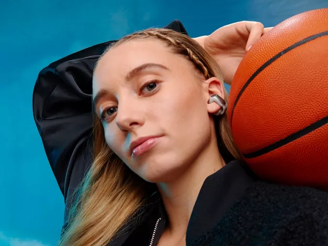 Paige Bueckers wearing Bose Ultra Open Earbuds while holding a basketball 