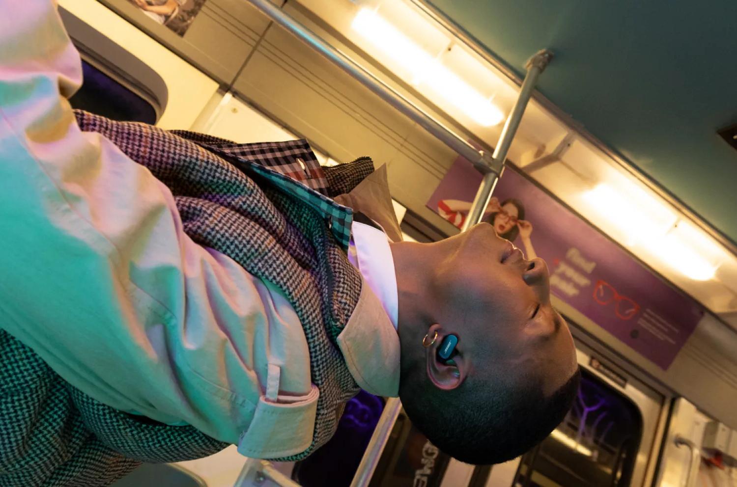 Man wearing QuietComfort Earbuds II on a subway train