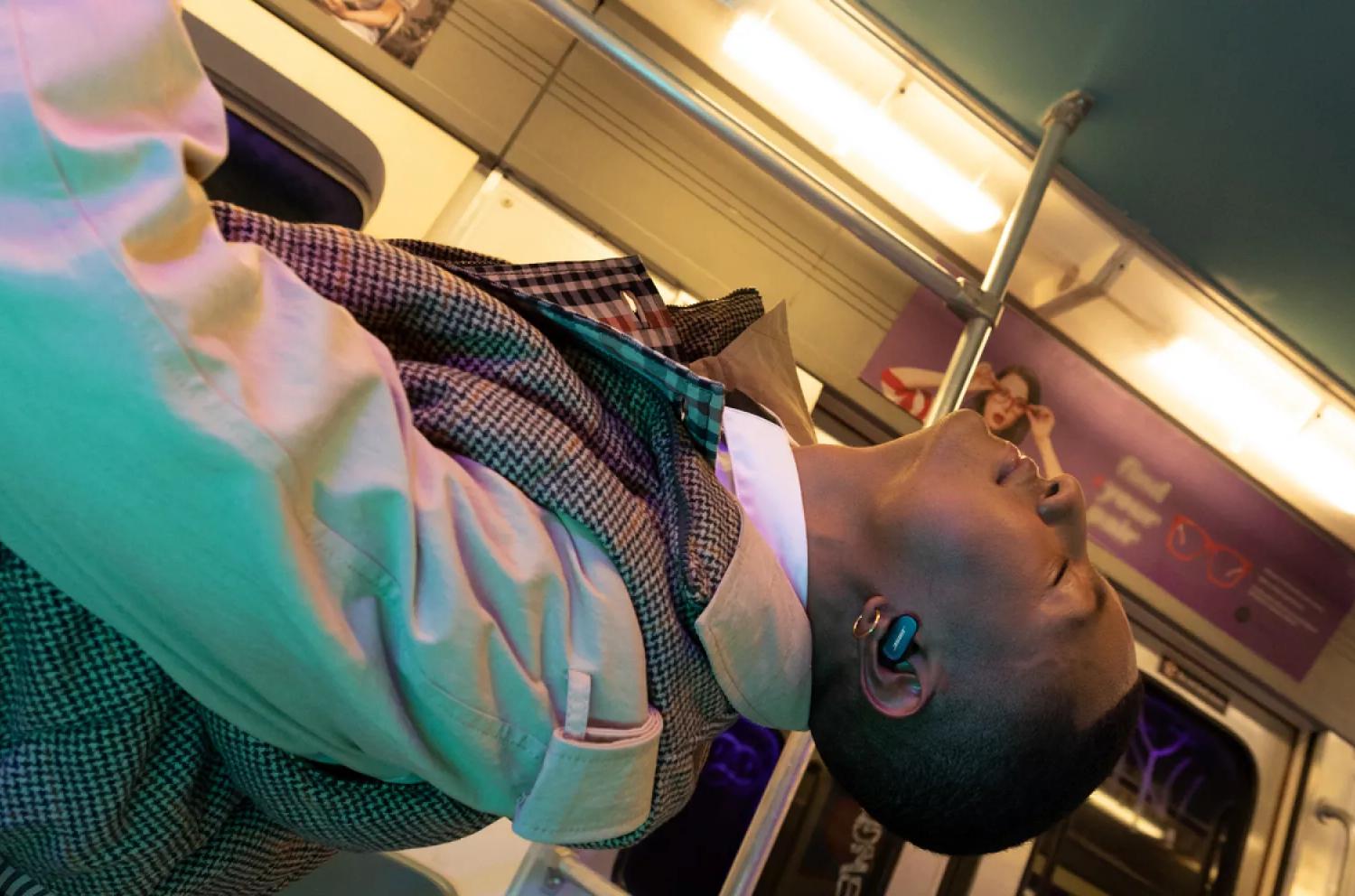 Man wearing QuietComfort Earbuds II on a subway train