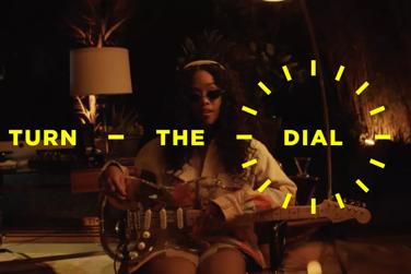 Turn the Dial. H.E.R. holding a guitar