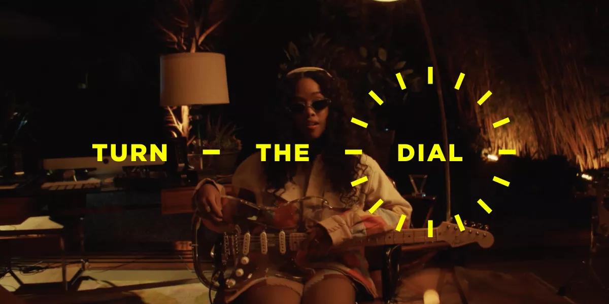 Turn the Dial. H.E.R. holding a guitar