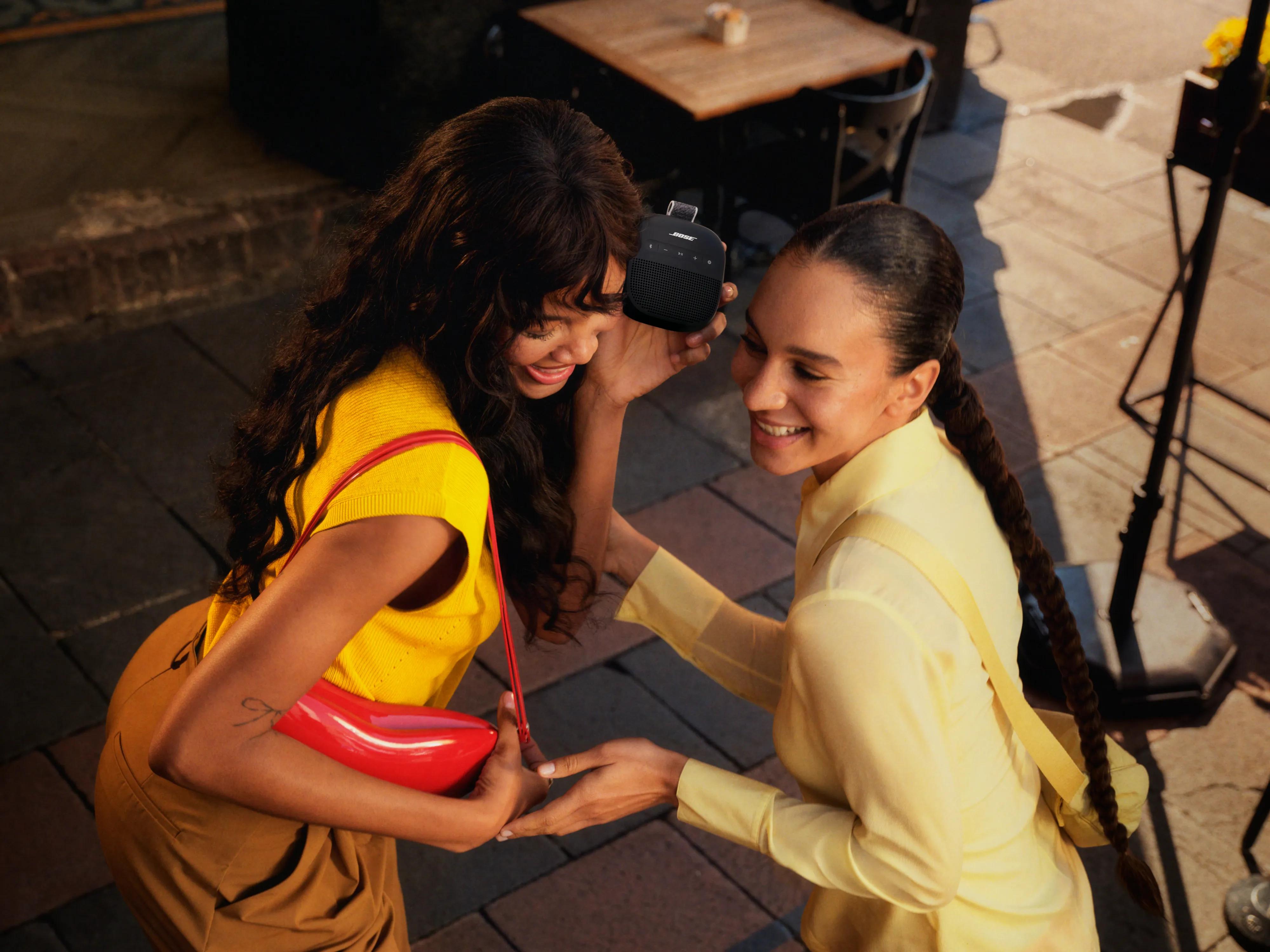 Two women listening to music with the SoundLink Micro Bluetooth Speaker (2nd Gen).