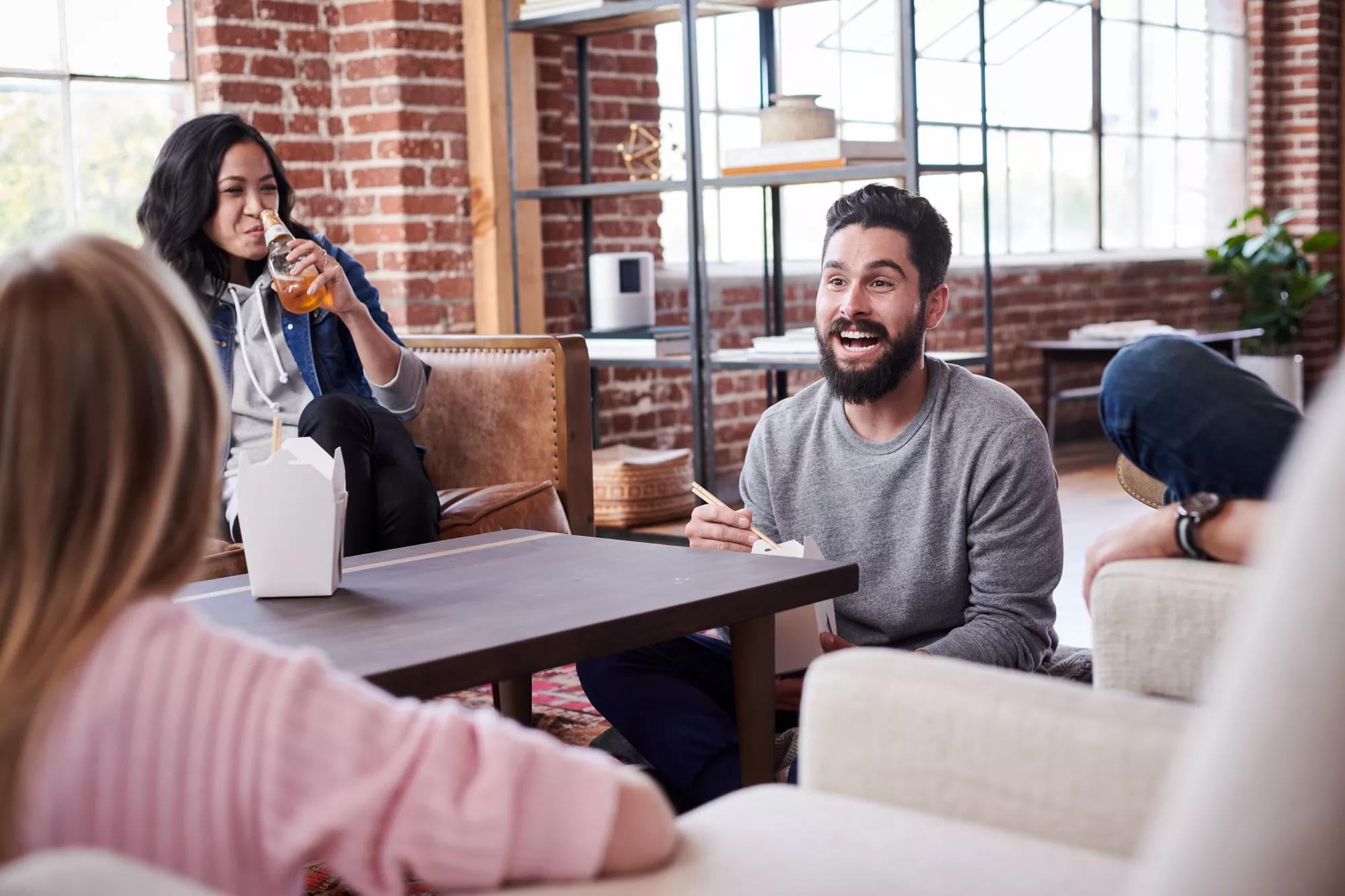 A group of friends sit around a coffee table and laugh