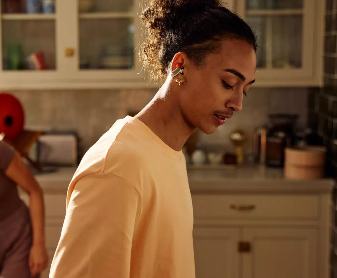 Man wearing Bose Ultra Open Earbuds while cleaning the kitchen with his wife