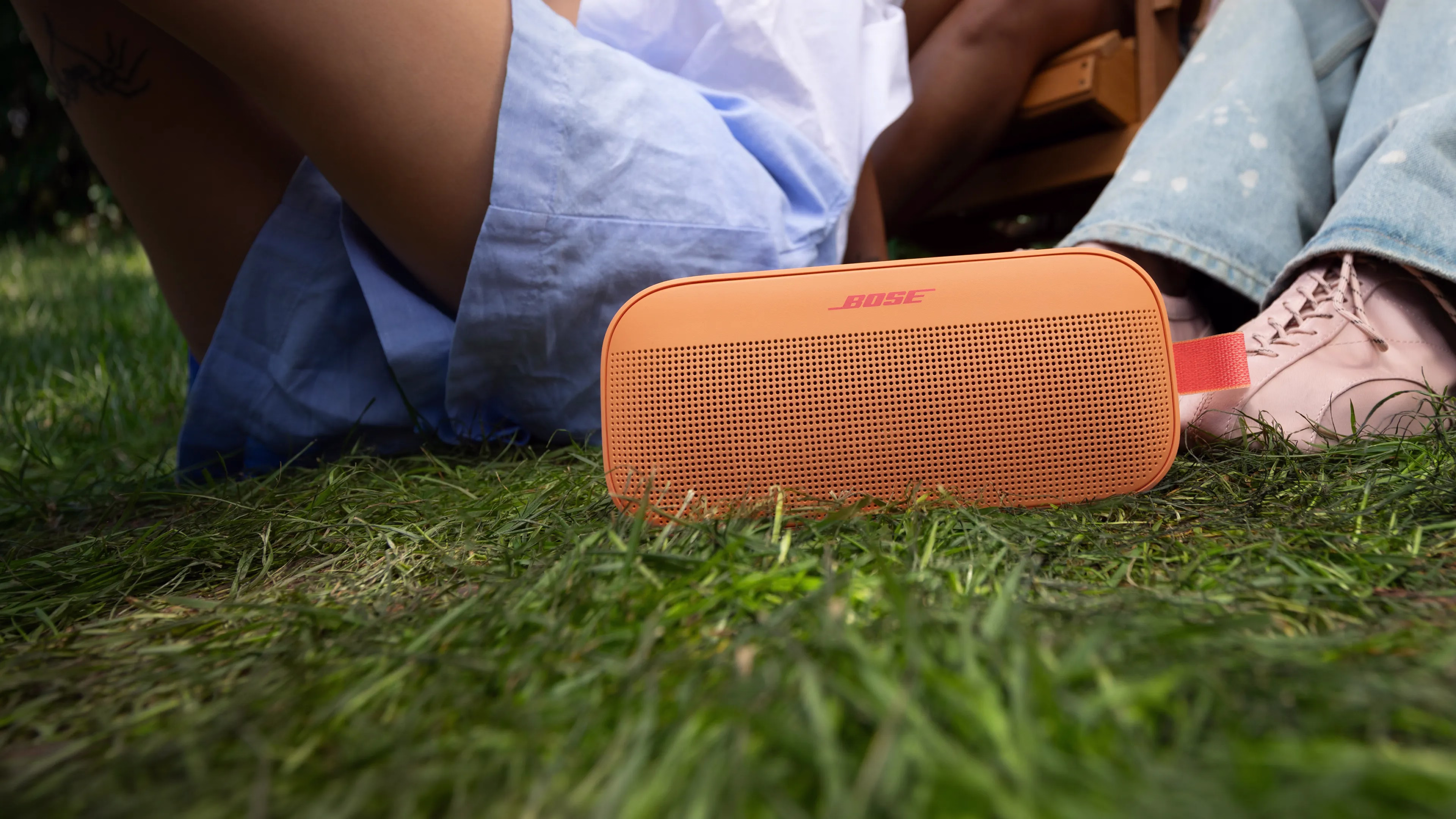 Personnes assises dans l&rsquo;herbe &eacute;coutant la musique d&rsquo;une enceinte portable Bose SoundLink Flex (2e&nbsp;g&eacute;n&eacute;ration) pos&eacute;e par terre.