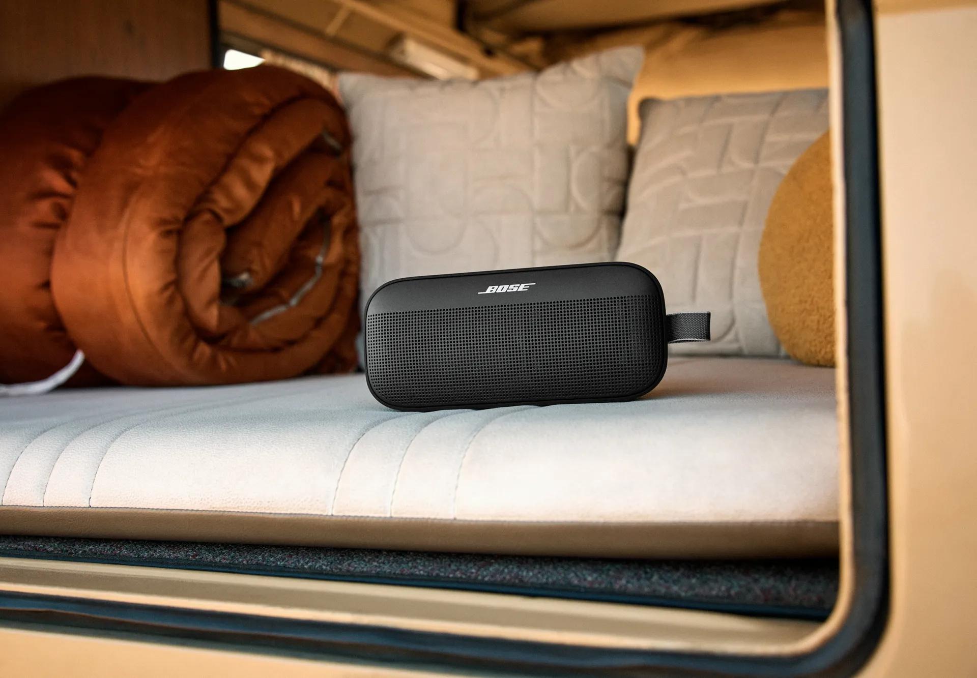 Bose SoundLink Flex Portable Speaker (2nd Gen) in the back of a van with pillows and a sleeping bag.