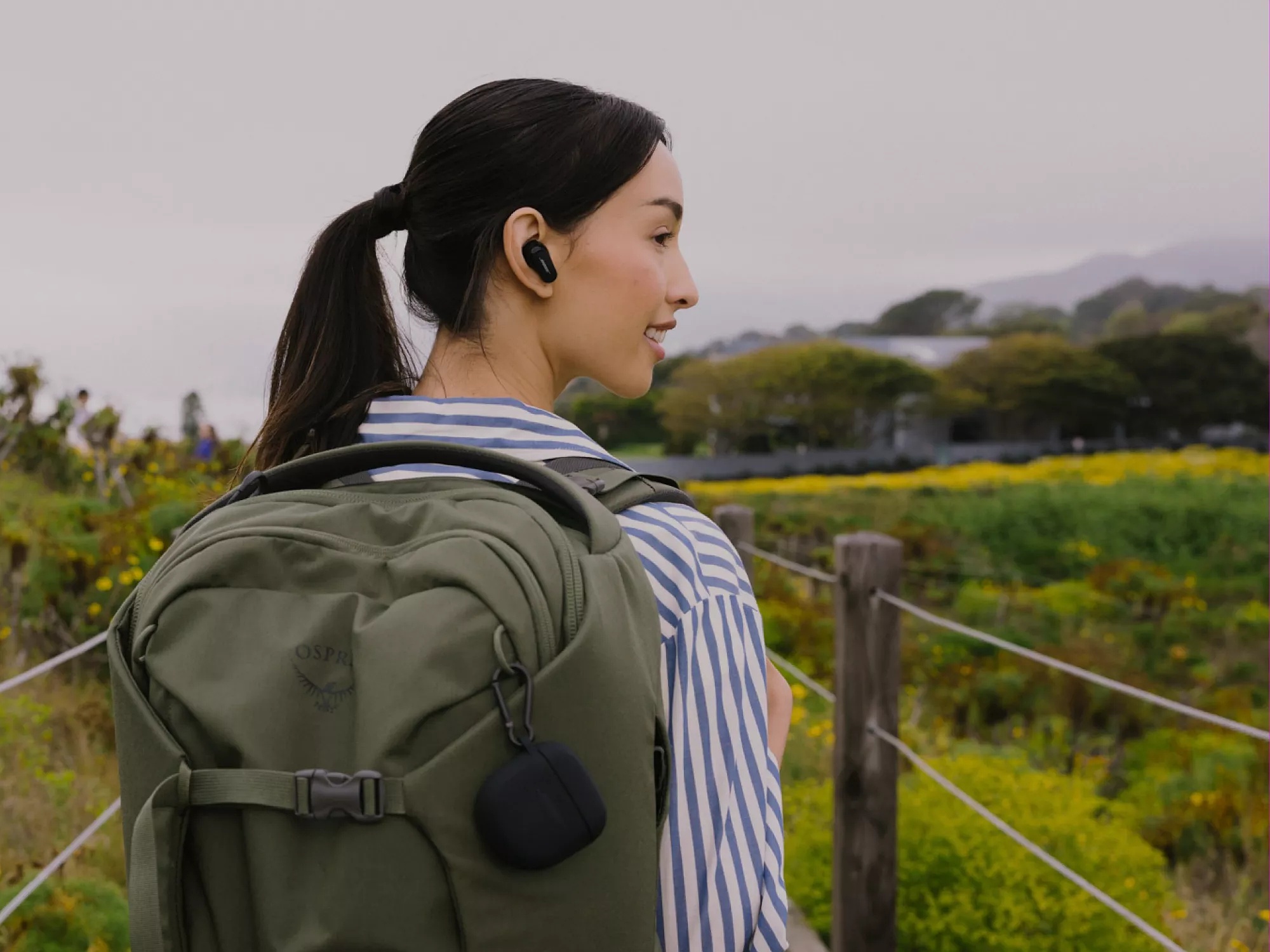 Woman on hike wearing backpack and listening to Bose QuietComfort Earbuds II