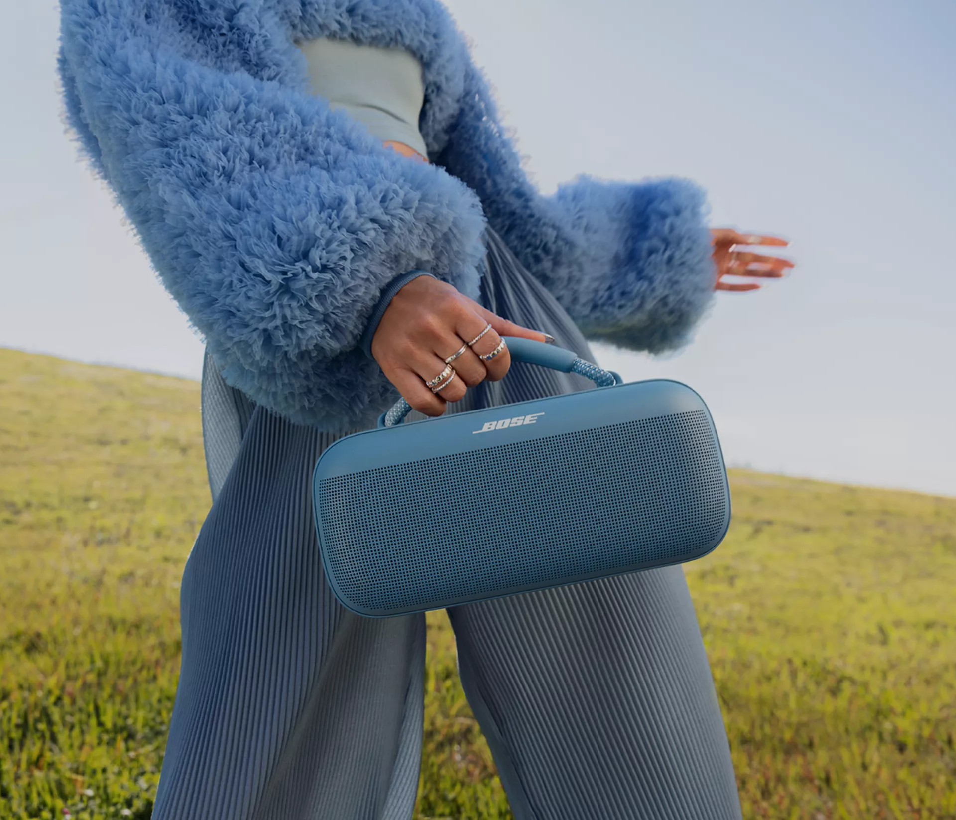 Woman carrying a Bose SoundLink Max Portable Speaker with the carry handle outside