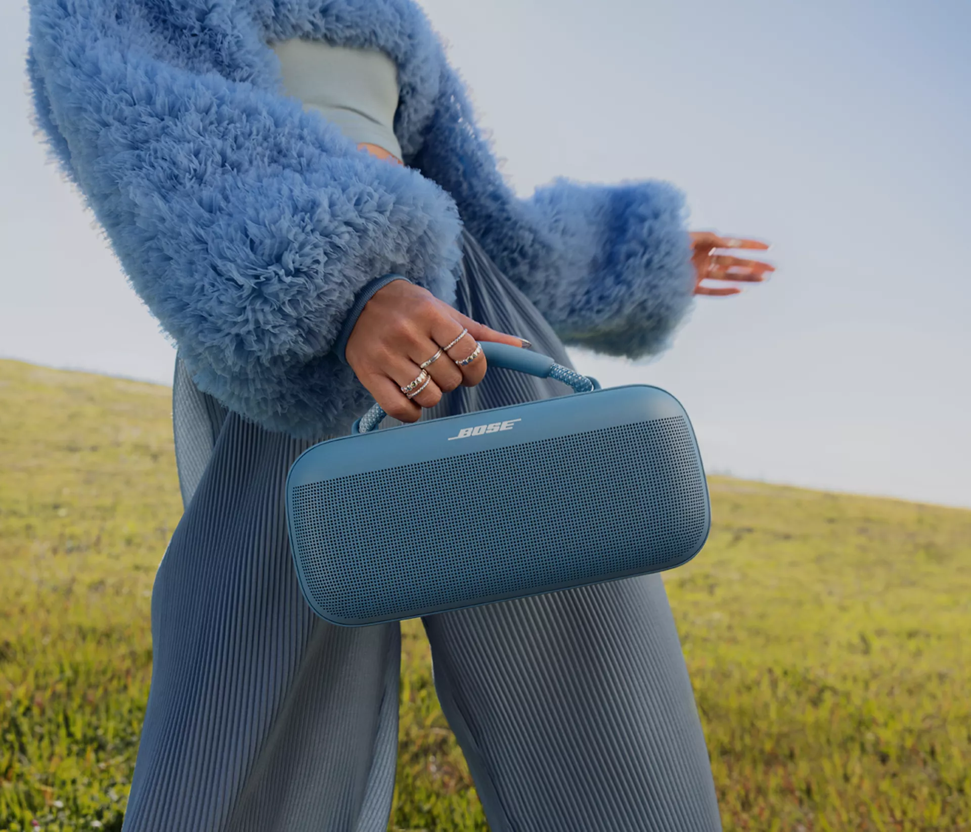 Mujer que lleva un altavoz portátil Bose SoundLink Max con el asa de transporte afuera