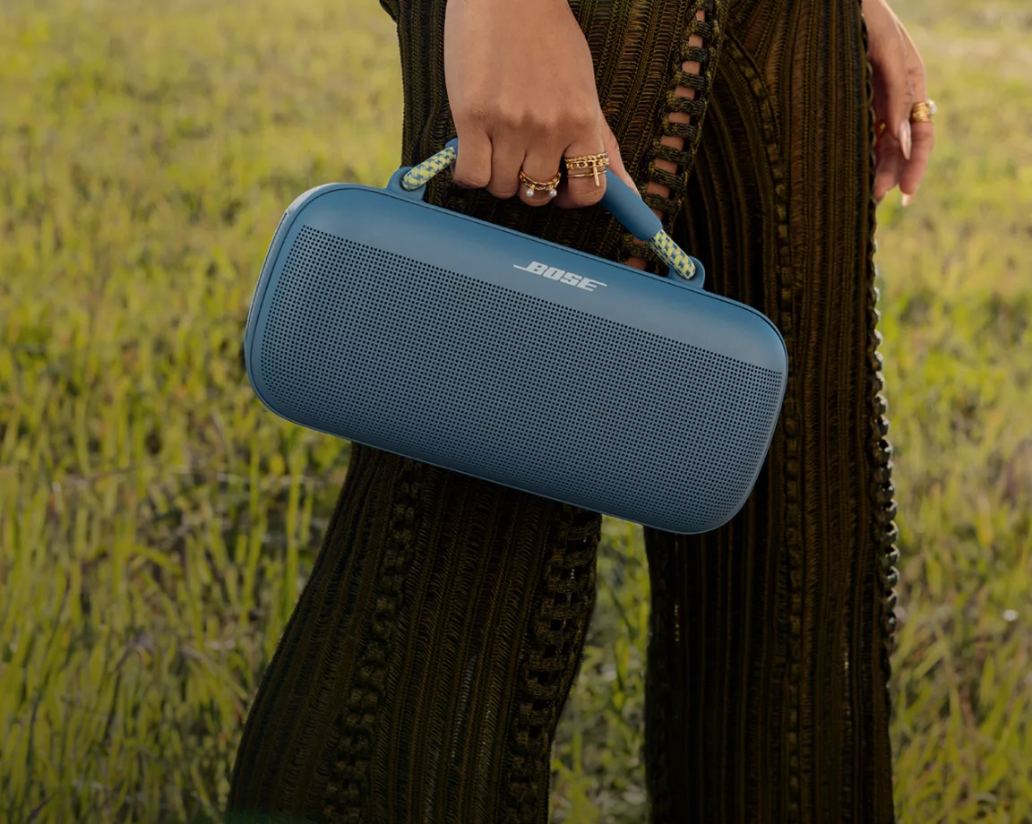 Person walking outside carrying a Bose SoundLink Max Portable Speaker with the carry handle 