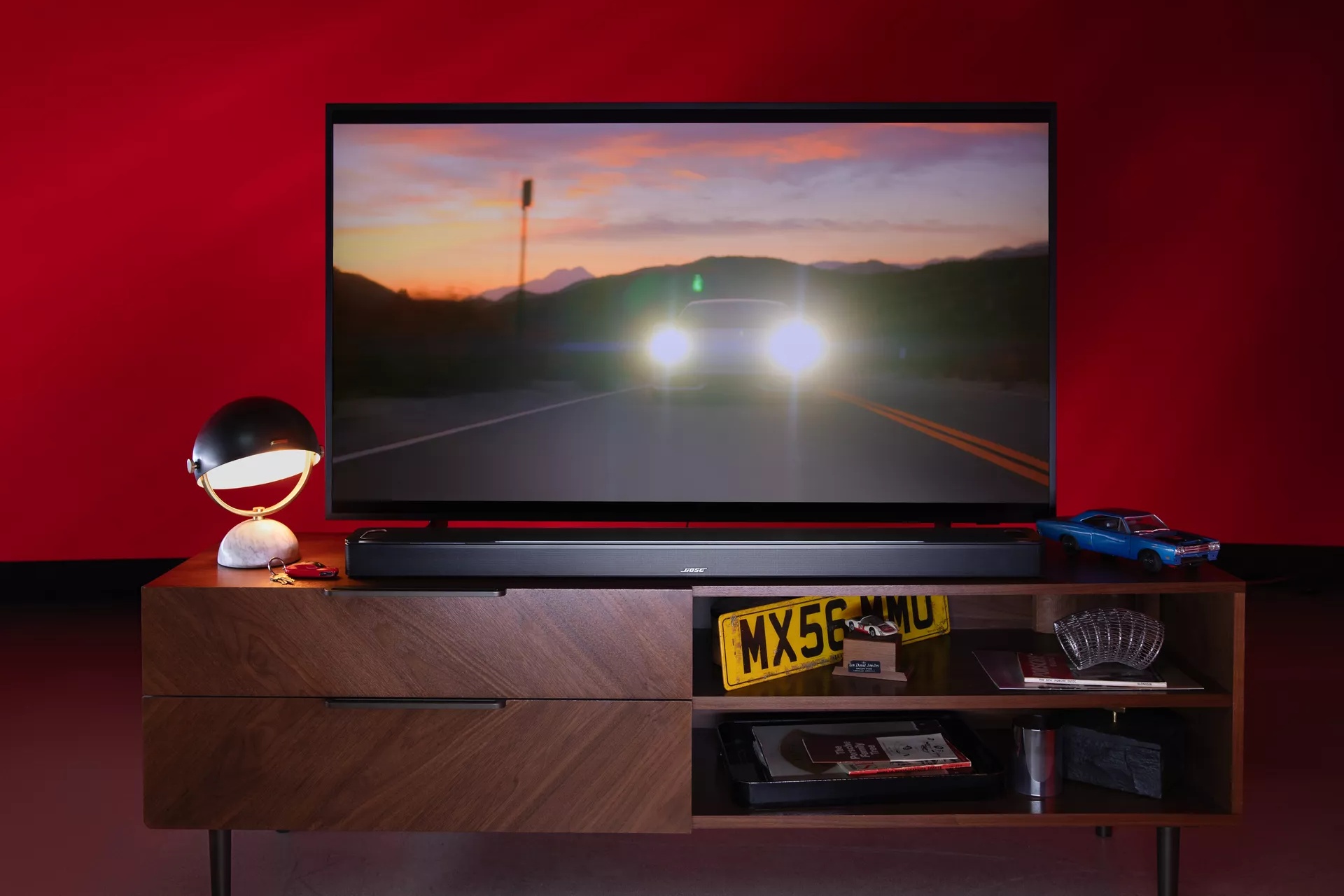 Bose Smart Ultra Soundbar on TV stand as a movie with a car plays on television