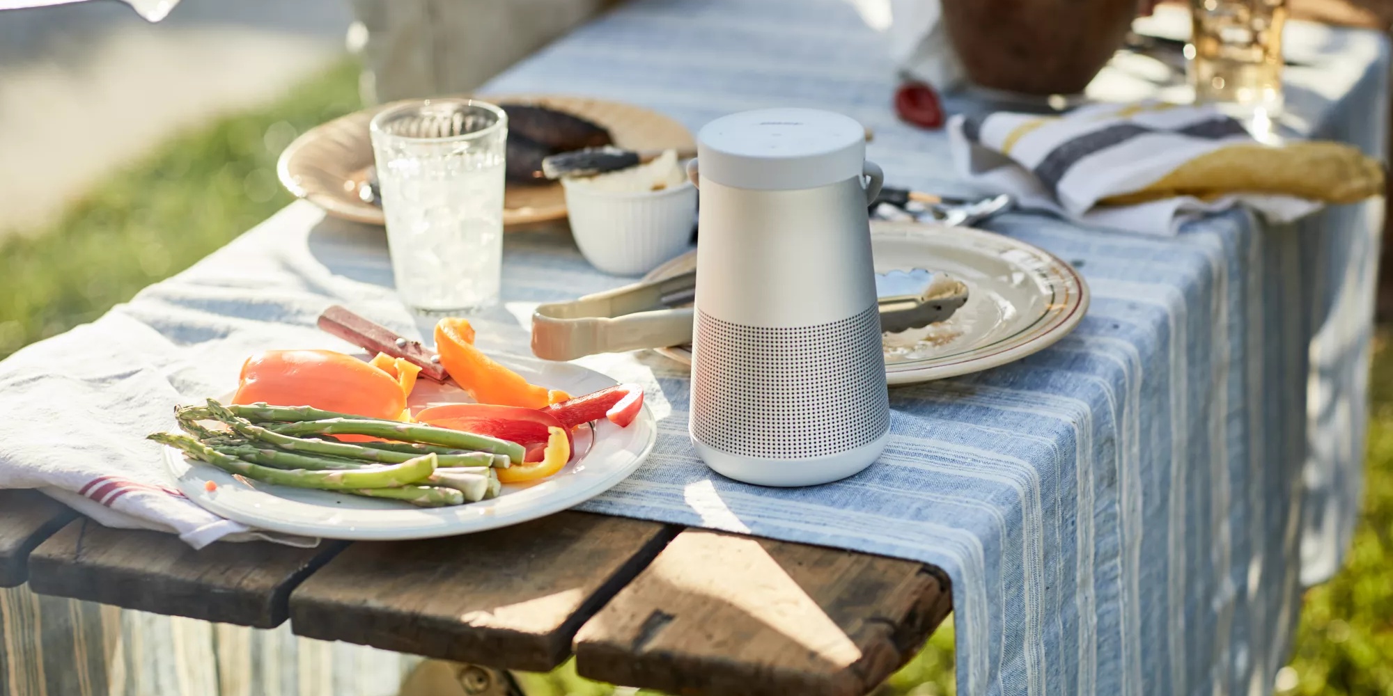 SoundLink Revolve+ II Bluetooth speaker on a table at an outdoor barbecue