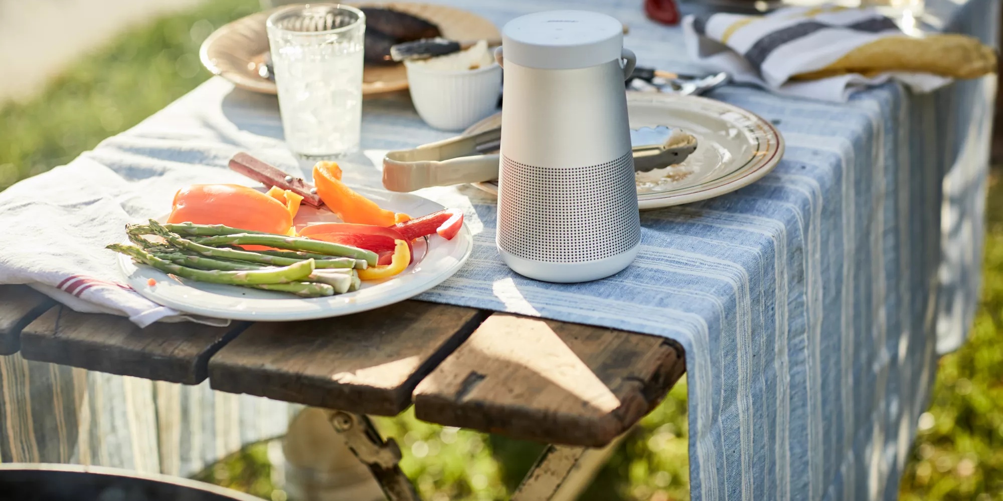 SoundLink Revolve+ II Bluetooth speaker on a table at an outdoor barbecue