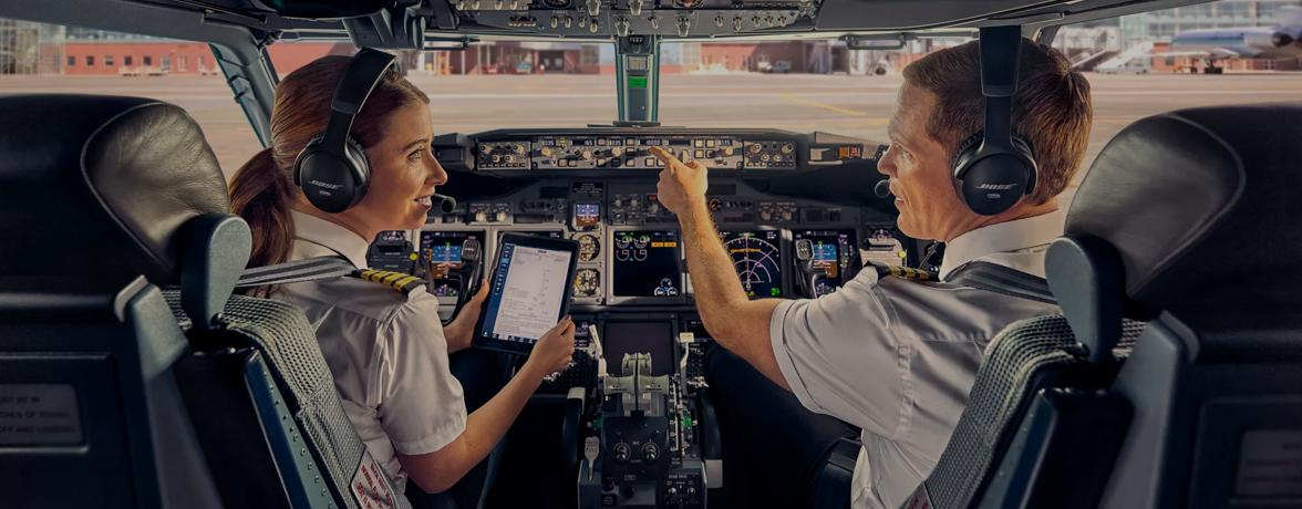 Pilot and copilot wearing Bose A30 Aviation Headsets discussing flight plans in the cockpit of an airplane