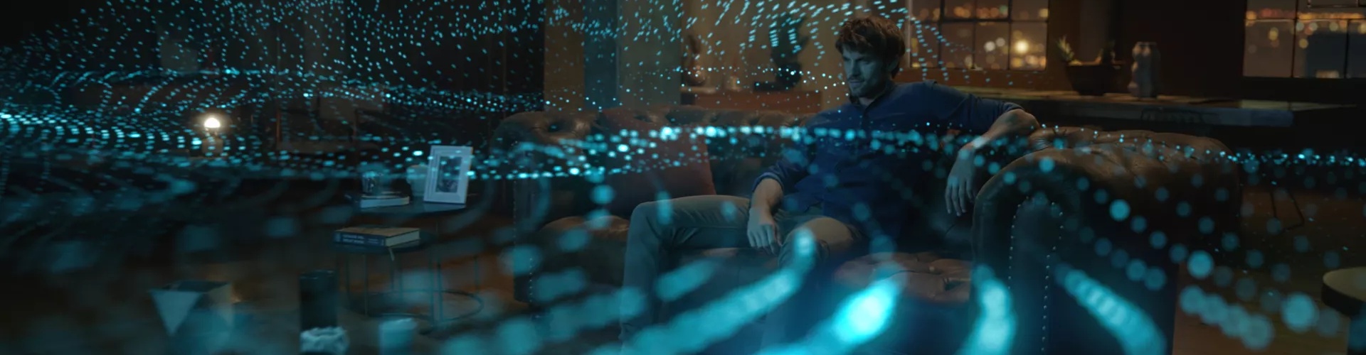 Homme dans un salon regardant la télévision avec les ondes sonores qui représentent la technologie Dolby Atmos émanant de la barre de son Bose