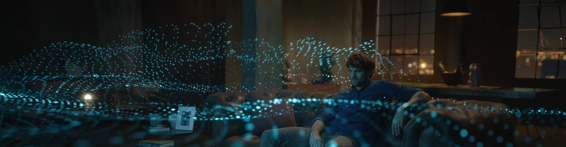 Man in a living room watching TV with soundwaves radiating from a Bose soundbar depicting Dolby Atmos