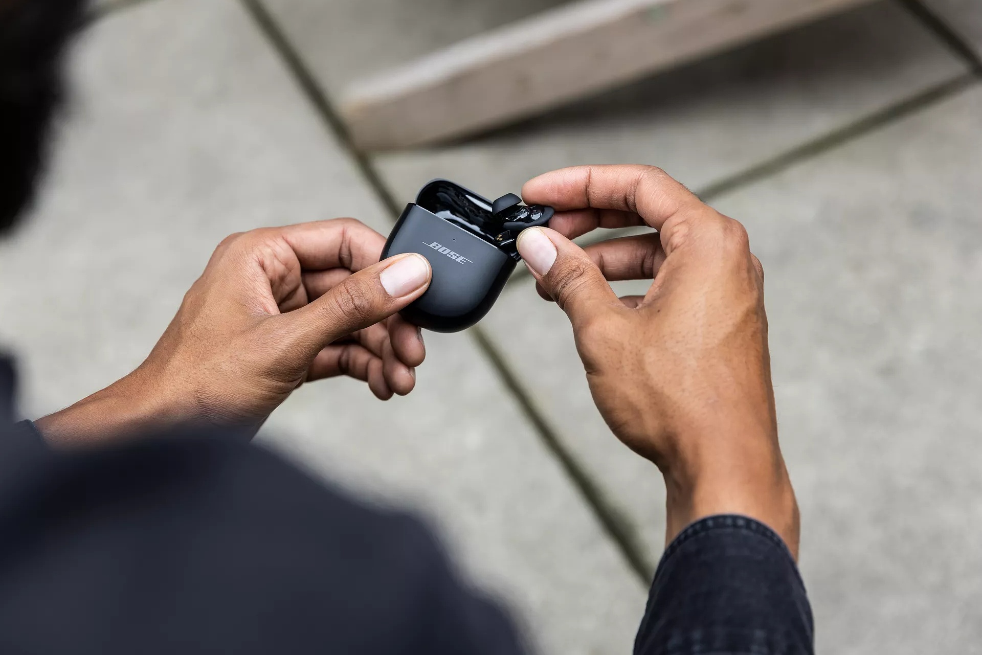 Person removing a QuietComfort Ultra Earbud from a charging case
